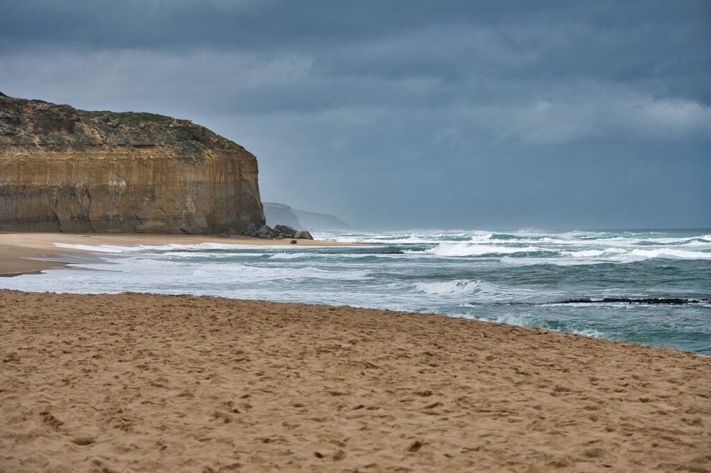 image d'une plage de sable fin, la mer monte et des vaguelettes blanchissent l'écume